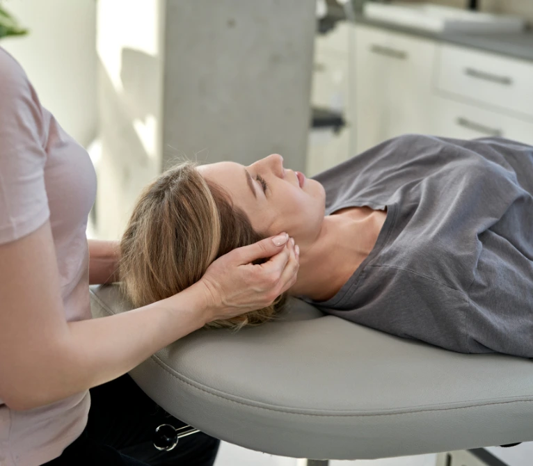 Frau erhält eine entspannende Behandlung in Rückenlage auf einer Therapieliege.